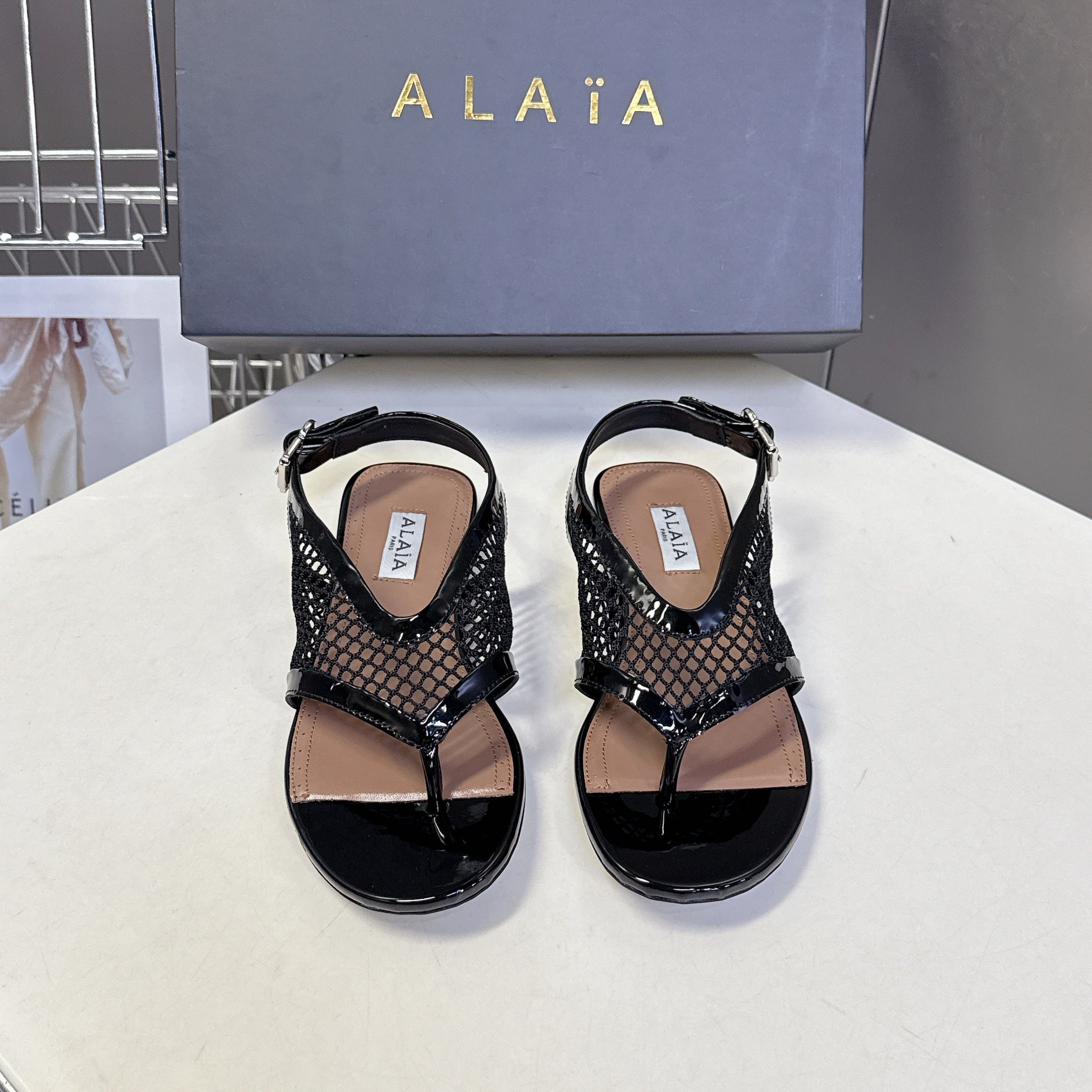 ALAIA 26S FLAT MESH THONG SANDALS IN BLACK PATENT CALFSKIN