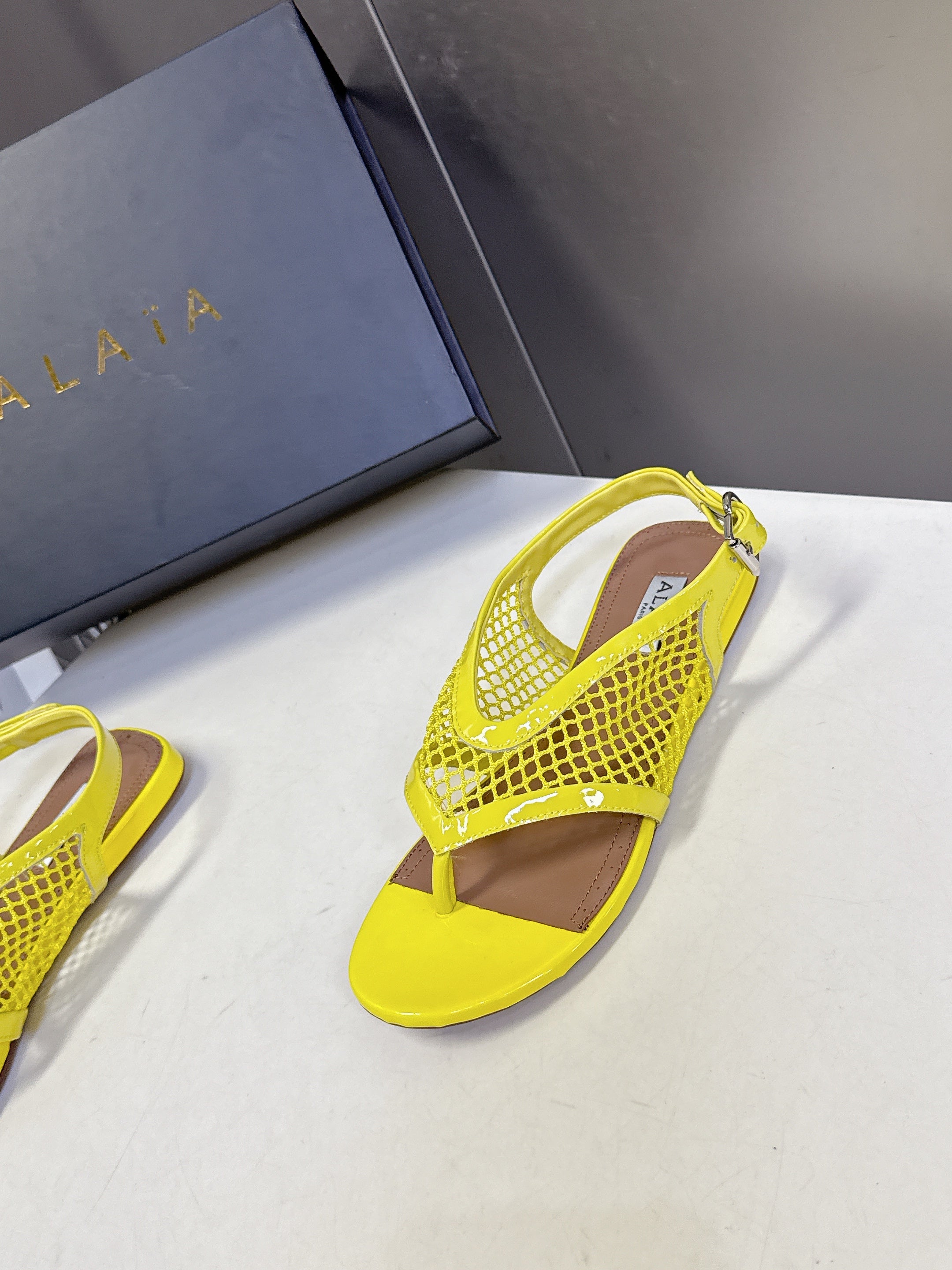 ALAIA 26S FLAT MESH THONG SANDALS IN YELLOW PATENT CALFSKIN