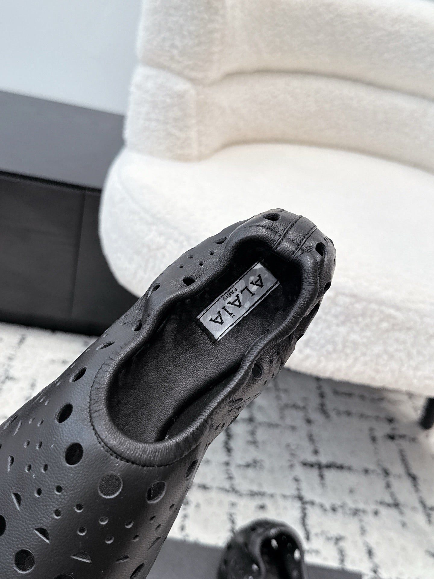 ALAIA 26S FLAT SLIP-ONS IN BLACK CALFSKIN WITH OPENWORK PATTERN