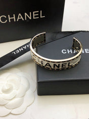 CHANEL 26S CHANEL LOGO ENAMEL CUFF BRACELET WITH BLACK TRIM IN GOLD METAL 630835